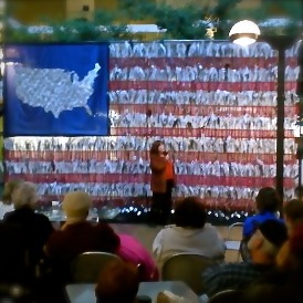 Be Involved_Story Flag Exhibit_photo of presenter in front of story flag at White Cane Day in Eugene, Oregon.